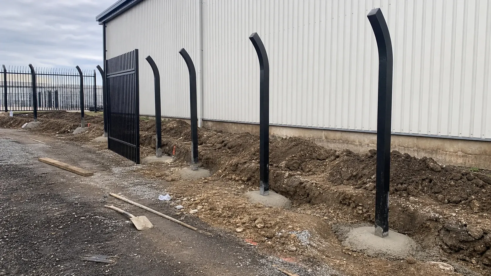bent top metal security fence posts installed in concrete foundations