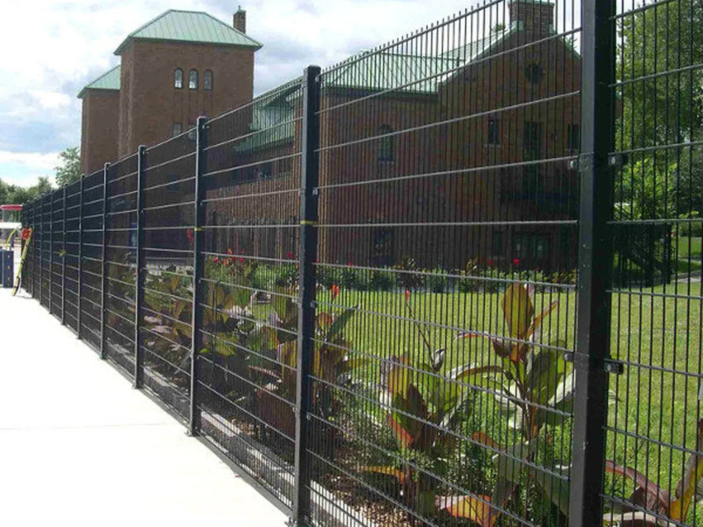 Double wire fence panel installed at a factory entrance with square posts and clamp fixings